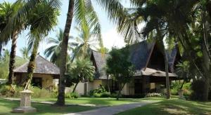 une maison avec des palmiers devant dans l'établissement Tanjung Lesung Beach Hotel, à Kalicaah