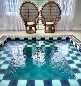 two chairs sitting next to a swimming pool at MiraNamin Nest LANTANA SUITE in Unique Historic Home with Garden Access, Rooftop, Bathtub, Private Kitchen in Manila