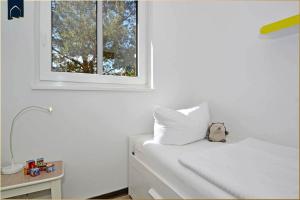 a bedroom with a white bed with a window at Waldsiedlung DHH Waldhaus 6 in Korswandt