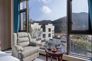 een woonkamer met een stoel en een groot raam bij 花筑庐江满山红遍民宿 