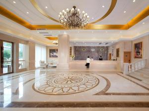 a man standing in a lobby with a chandelier at Vienna Hotel Guangdong Qingyuan Wanda Plaza Xincheng Beijiang in Qingyuan