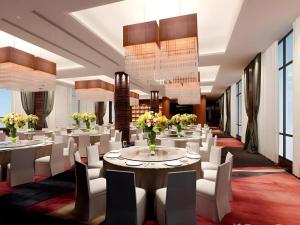 un restaurant avec des tables blanches et des chaises blanches dans l'établissement Fuzhou Fliport Garden Hotel, à Xianqi