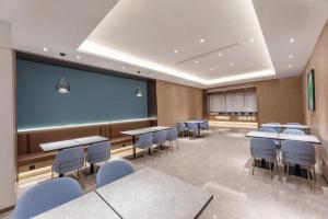 a classroom with tables and chairs and a large screen at GreenTree Inn JiangSu NanJing South Railway Station South Square Express Hotel in Jiangning