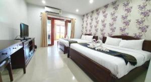 a bedroom with two beds and a flat screen tv at Doungta Anda Hotel Krabi in Ban Khlong Chi Lat