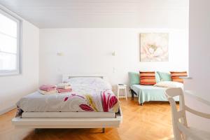 a white bedroom with a bed and a couch at Chambres d’hôtes Chantal Hereaudeau in Les Moulins de la Boire