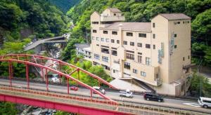 un pont rouge sur une autoroute avec un bâtiment dans l'établissement Hotel Obokekyo Mannaka, à Miyoshi