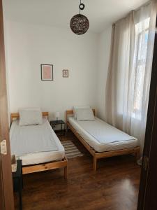two twin beds in a room with a window at Radomir Downtown 1-bedroom Apartment with balcony in Bŭnzareto