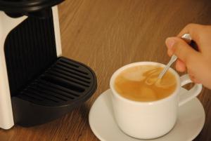 a person stirring a cup of coffee with a spoon at SeewinkelZimmer by Sabines Apartments Frauenkirchen in Frauenkirchen +9 photos