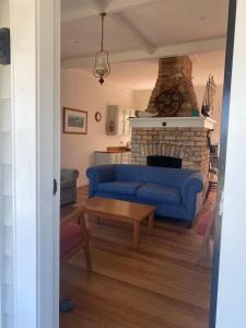a living room with a blue couch and a fireplace at Russell Waterfront Historic Cottage in Russell