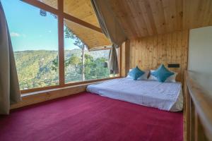 a bedroom with a bed with a large window at The Trishul Vista in Mukteshwar