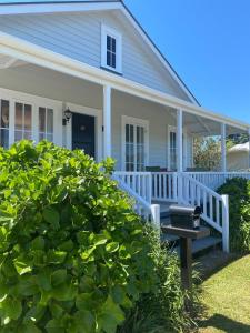 a house with a white porch and a grill at Russell Waterfront Historic Cottage in Russell