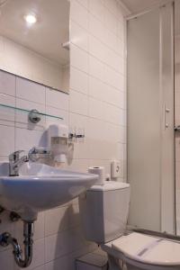 Un baño blanco con lavabo e inodoro. en Hotel CB Royal, en České Budějovice