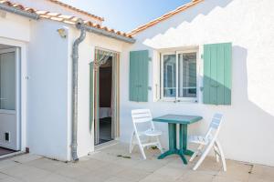 a patio with two chairs and a table in front of a house at Chambres d’hôtes Chantal Hereaudeau in Les Moulins de la Boire