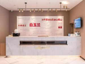 a restaurant counter with a large wall with writing on it at Magnotel Business Harbin Railway Station Qiulin Museum Metro Station in Harbin