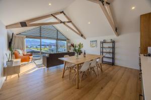 a kitchen and living room with a table and chairs at Aspiring View Apartments - Modern & Stylish 3-BRM, 3-BTH - 2 Min Walk to Lake & Town in Wanaka