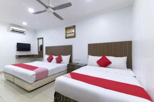 a bedroom with two beds with red and white sheets at OYO 90623 Thank Q Inn 3 in Kota Bharu