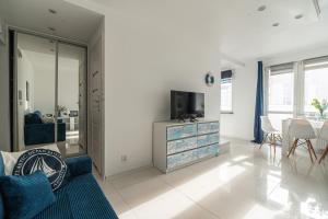 a living room with a tv and a blue couch at Apartly - Apartament Wyszyńskiego z loggią in Szczecin