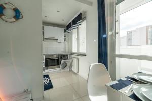 a kitchen with white appliances and a large window at Apartly - Apartament Wyszyńskiego z loggią in Szczecin