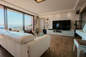 a living room with a white couch and a television at Appartment - Panoramic Sea View - Swimming Pool in Villefranche-sur-Mer