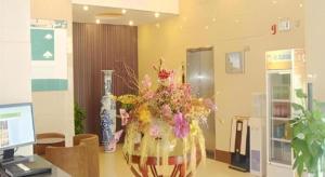 a vase filled with flowers sitting on a desk at GreenTree Inn Zhoushan New Town Hotel in Zhoushan