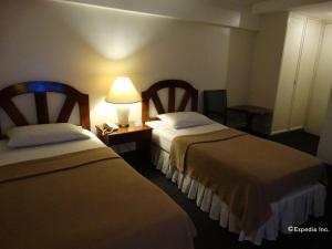 マニラにあるAdriatico Arms Hotelのベッド2台とランプ付きのテーブルがあるホテルの部屋 +90枚の写真