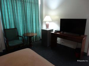 マニラにあるAdriatico Arms Hotelのベッド、テレビ、椅子が備わるホテルルームです。