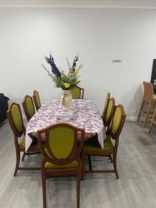 Una mesa de comedor con un jarrón de flores encima. en Quiet Spacious Family House, en Rooty Hill