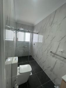 Un baño blanco con inodoro y lavabo. en Quiet Spacious Family House, en Rooty Hill