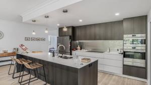 een keuken met witte kasten en een keukeneiland met krukken bij Salt & Sand Sanctuary in Woorim