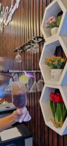 a person holding a wine glass in a room with flowers at The River khaosok in Khao Sok