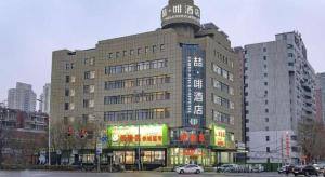 un grand bâtiment avec un panneau en haut dans l'établissement James Joyce Coffetel Shenyang North Railway Station Qishan Road Metro Station, à Shenyang