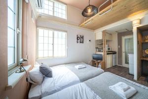 een slaapkamer met twee bedden en twee ramen bij Guest House NANMO in Minami-jūichijō