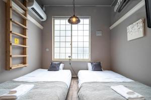 twee bedden in een kamer met een raam bij Guest House NANMO in Minami-jūichijō