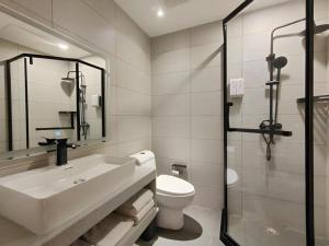 a bathroom with a sink and a toilet and a shower at GreenTree Inn Shanxi Jinzhong JieXiu Railway Station Express Hotel in Jiexiu