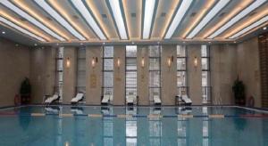 une piscine avec des chaises dans un immeuble dans l'établissement New Century Grand Hotel Xi'an Xizang Building, à Xi'an