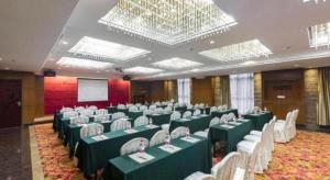 une salle de conférence avec des tables vertes et des chaises blanches dans l'établissement Vienna International Hotel Dongguan Changping Tian'ehu Road, à Dongguan