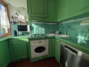a green kitchen with a stove and a sink at Casa Stocke - Relax e natura in Contrà Zocchi in Asiago +43 photos