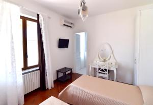 B&B Home Sweet Home Rosolini في روسوليني: غرفة نوم بيضاء مع سرير ومرآة