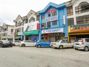 Kampong MahangにあるOYO 89406 Lucky Budget Hotelの建物前に停車する車両群