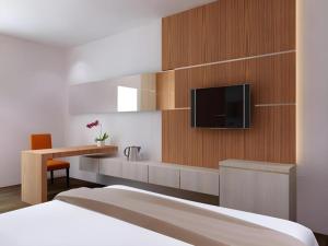 a bedroom with a bed and a desk and a tv at Neotel Hotel City Centre in Tanjungredep