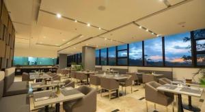 Camp John HayにあるThe Plaza Lodge Baguioの白いテーブルと椅子と窓のあるレストラン