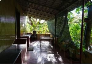 a room with a bench and a window with trees at The Whistling Pine Woods in Varagampadi