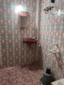 a bathroom with a sink and a tile wall at The Whistling Pine Woods in Varagampadi