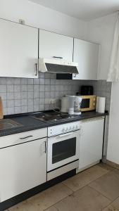 une cuisine avec des armoires blanches et un four à plaques de cuisson dans l'établissement Ruhiges Apartment in Dresdner Neustadt, à Dresde 13 autres photos
