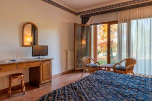 a bedroom with a bed and a desk with a television at Fattoria degli Usignoli in San Donato in Fronzano