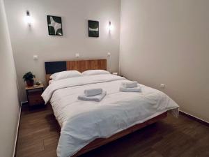 a bedroom with a large white bed with towels on it at Hodos Luxury APT 2 near ATH-Airport in Markopoulo +4 photos