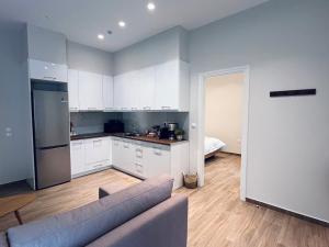 a kitchen with white cabinets and a couch in a room at Hodos Luxury APT 2 near ATH-Airport in Markopoulo