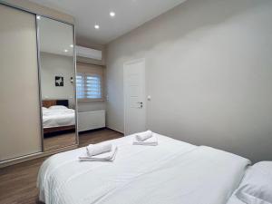 a bedroom with a large white bed and a mirror at Hodos Luxury APT 2 near ATH-Airport in Markopoulo