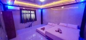 a room with two beds in a room with purple lights at Vel Serene Villa in Panglao Island