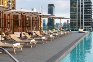 a pool with chairs and umbrellas on top of a building at Grande Centre Point Prestige Bangkok in Bangkok